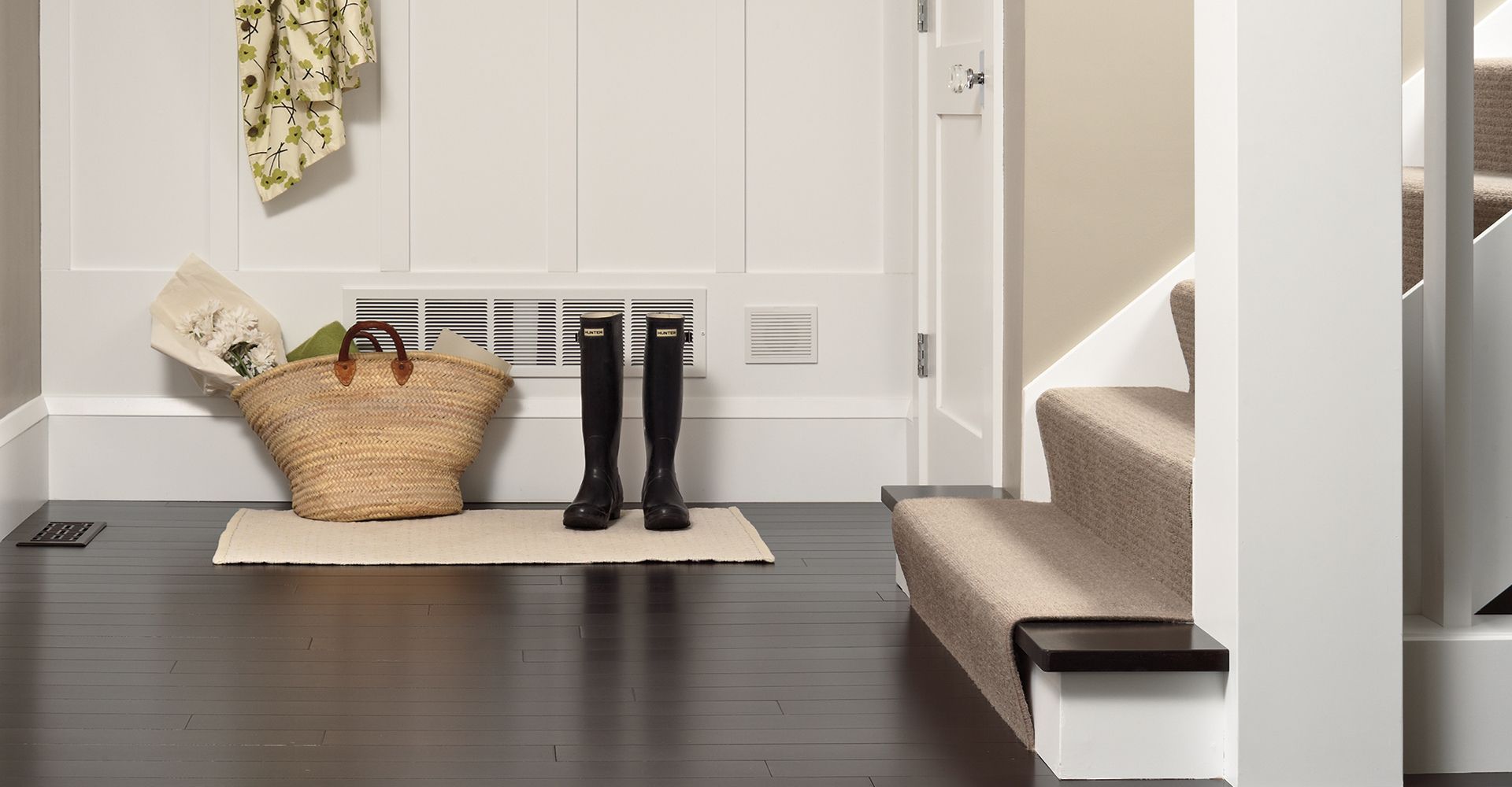 wood flooring in entryway by staircase with stair runners